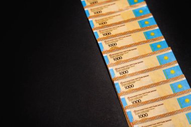 1000 tenge 'lik banknotların bir çok parçası arka arkaya serildi. Nakit. Siyah arkaplan                 