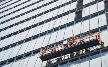 Almaty, Kazakistan - 29 Nisan 2025: Vitray döşeyen işçilerle birlikte inşaat beşiği. Cam cephe                            