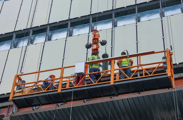 Almaty, Kazakistan - 29 Nisan 2025: İnşaat beşiğindeki işçiler cam krikoya sahip bir pencere kurdular. Dış görünüş                               