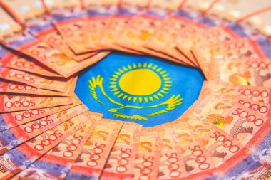 Katlanmış tenge banknotları çemberinde Kazakistan bayrağının sembolleri. Devlet finansmanı                         