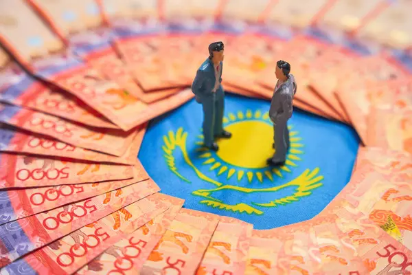 Kiralık banknotlar arasında Kazak bayrağında duran iki iş adamı figürü. İş görüşmeleri. Yönetmenlerin toplantısı                               