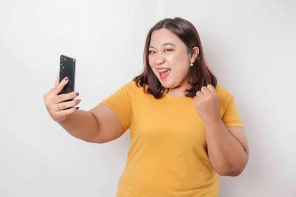 Portret Szczęśliwej Azjatki Dużych Rozmiarach Uśmiecha Się Trzyma Smartfona Żółtej — Zdjęcie stockowe