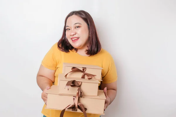 幸せな若いアジアの大きなサイズの女性は黄色のシャツを着て プレゼントボックスとショッピングバッグを保持しています — ストック写真