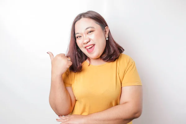 身穿黄色衬衫的兴奋的亚洲大个子女人伸出大拇指表示同意的手势 与白色背景隔离 — 图库照片
