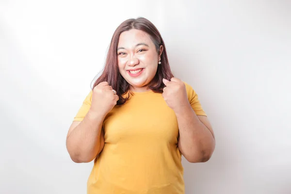 白い背景に孤立した黄色のシャツを着た幸せな表情をした若いアジア系の巨乳女性 — ストック写真