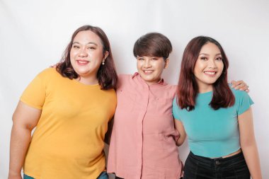 Üç arkadaşın portresi gülümsüyor, beyaz arka planla izole edilmiş mutlu duyguları ifade ediyor.