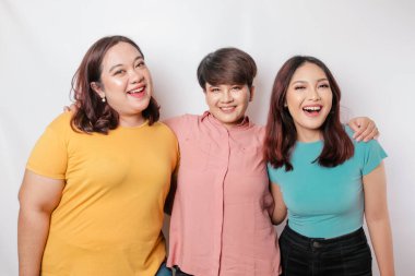 Üç arkadaşın portresi gülümsüyor, beyaz arka planla izole edilmiş mutlu duyguları ifade ediyor.