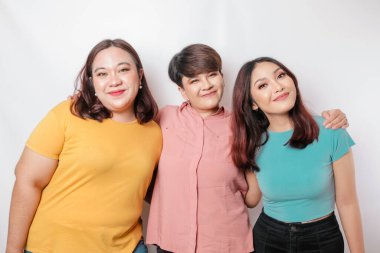 Üç arkadaşın portresi gülümsüyor, beyaz arka planla izole edilmiş mutlu duyguları ifade ediyor.