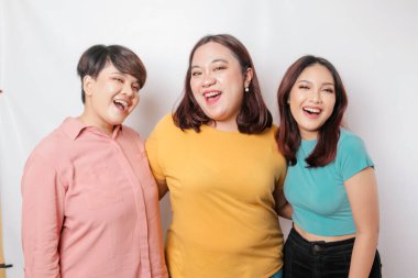 Üç arkadaşın portresi gülümsüyor, beyaz arka planla izole edilmiş mutlu duyguları ifade ediyor.