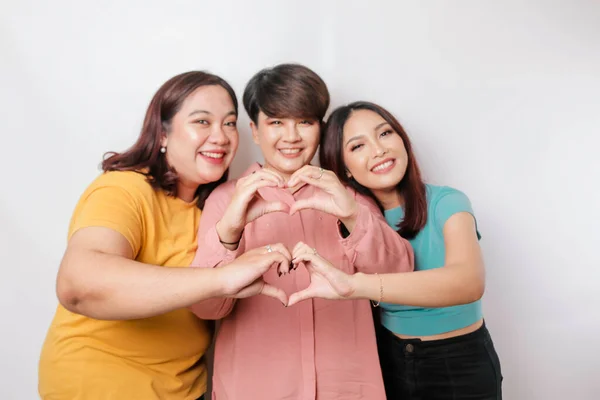 Three Asian women feel happy and a romantic shapes heart gesture expresses tender feelings, close friendship concept.