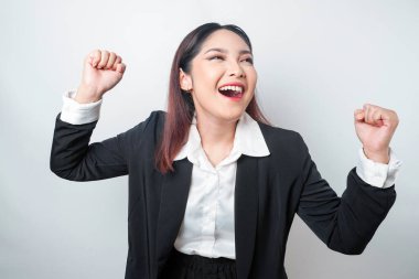 Asyalı genç bir iş kadını mutlu ve başarılı bir yüzle siyah takım elbise giyiyor.