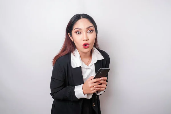 Έκπληκτη Ασιάτισσα Επιχειρηματίας Φορώντας Μαύρο Κοστούμι Κρατώντας Smartphone Της Απομονωμένη — Φωτογραφία Αρχείου