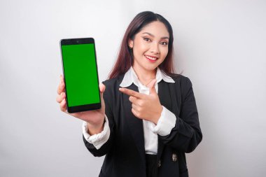 Mutlu genç bir iş kadını siyah takım elbise giyiyor, telefonunda beyaz arka planla izole edilmiş fotokopi alanı gösteriyor.