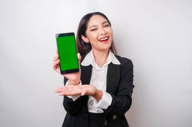 Mutlu genç bir iş kadını siyah takım elbise giyiyor, telefonunda beyaz arka planla izole edilmiş fotokopi alanı gösteriyor.
