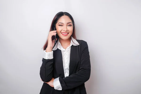 一位快乐的亚洲女商人的画像 穿着一身白色背景的黑色西服 一边打电话一边笑着 — 图库照片