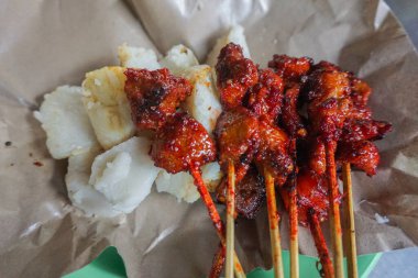 Lontong adlı pirinç keki ile domuz satayının portresi.