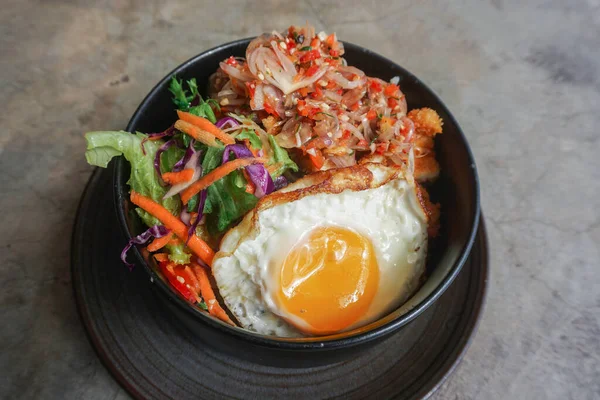 stock image A portrait of a rice bowl with Balinese sauce called sambal matah on a black bowl isolated by concrete background