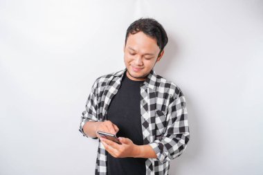 Asyalı mutlu bir adamın portresi beyaz arka planla izole edilmiş telefonunu tutarken gülümsüyor.