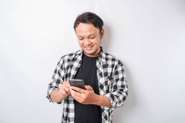 Asyalı mutlu bir adamın portresi beyaz arka planla izole edilmiş telefonunu tutarken gülümsüyor.