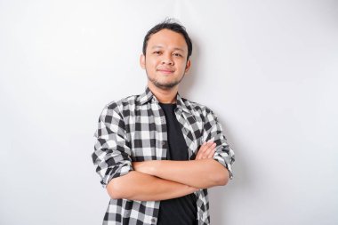 Kollarını kavuşturup beyaz arka planda izole edilmiş kameraya bakan ve kendinden emin gülümseyen Asyalı bir adamın portresi.