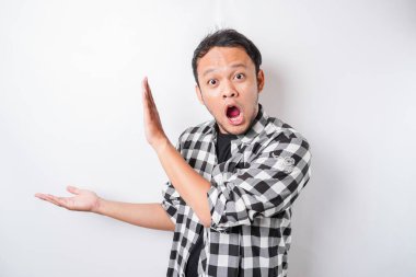 Şok olmuş Asyalı adam beyaz arka planla izole edilmiş, yanındaki fotokopi alanını gösteriyor.