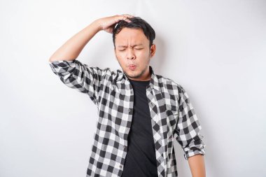 Asyalı stresli bir adamın beyaz arkaplanla izole edilmiş ekose gömlek giymiş portresi depresif görünüyor.