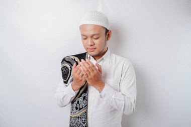 Omzunda dua halısı olan yakışıklı Asyalı Müslüman adam Tanrı 'ya dua ediyor..
