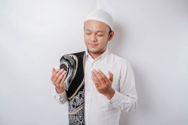 Omzunda dua halısı olan yakışıklı Asyalı Müslüman adam Tanrı 'ya dua ediyor..