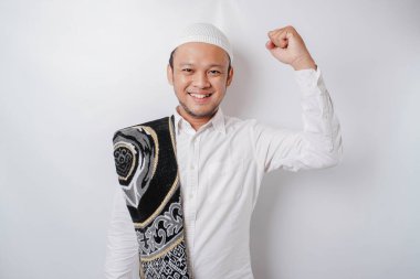 Omzunda dua halısı olan mutlu bir Asyalı genç Müslüman beyaz arka planla izole edilmiş başarılı bir yüz ifadesi sergiliyor.