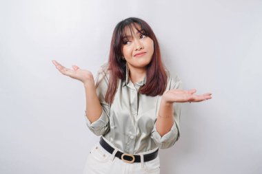 Düşünceli genç bir kadın yeşil bir gömlek giyiyor ve çenesini beyaz arka planda tutuyor.