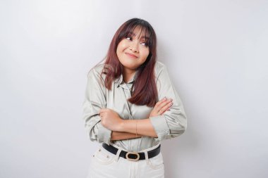 Düşünceli genç bir kadın yeşil bir gömlek giyiyor ve çenesini beyaz arka planda tutuyor.