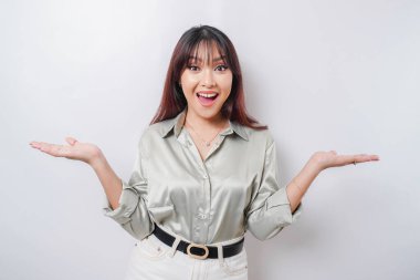 Heyecanlı Asyalı kadın adaçayı yeşili gömlekli, yanındaki fotokopi alanını işaret ediyor, beyaz arka planla izole edilmiş.