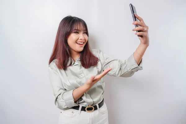 stock image A portrait of a happy Asian woman wearing a sage green shirt and holding her phone, isolated by white background