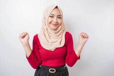 Mutlu bir ifadeyle genç bir Asyalı Müslüman kadın beyaz arka planla izole edilmiş tesettür takıyor.