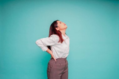 Sırt ağrısı çeken, iş yerinde kas spazmı geçiren yorgun bir genç kadın. Yorgunluk, teslim tarihi, acı ve yanlış duruş