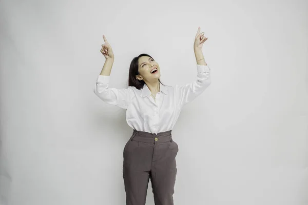 stock image Excited Asian woman wearing white shirt pointing at the copy space on top of her, isolated by white background