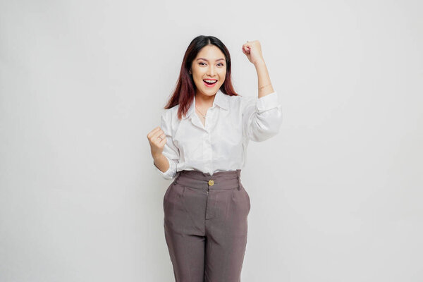 A young Asian woman with a happy successful expression wearing white shirt isolated by white background