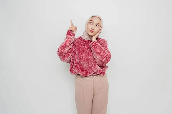 ピンクのセーターとヒジャーブを着た衝撃的なアジアのイスラム教徒の女性が彼女の上にコピースペースを指して 白い背景によって隔離されました — ストック写真