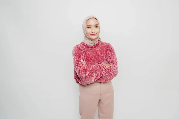 一个自信微笑的亚洲穆斯林女人的画像 她身穿粉色毛衣 头戴头巾 双手交叉地站在一起 看着被白色背景隔开的相机 — 图库照片