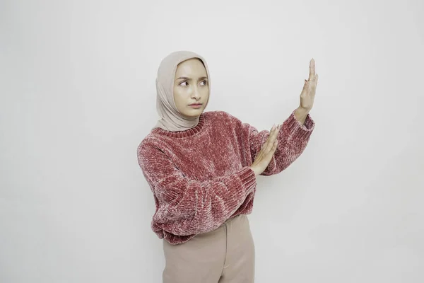 ピンクのセーターとヒジャーブを着た衝撃的なアジアのイスラム教徒の女性は 白い背景によって隔離され 彼女の横のコピースペースを指して — ストック写真