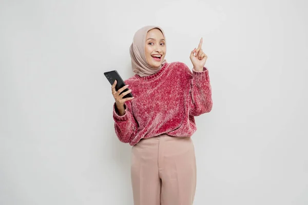스웨터를 히잡을 흥분한 아시아 핸드폰을 복사본 공간을 가리켰다 — 스톡 사진