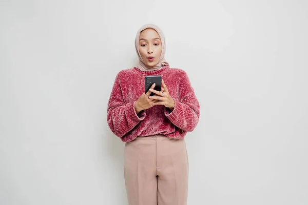 Шокированная Азиатка Розовом Свитере Хиджабе Держит Телефон Изолированный Белым Фоном — стоковое фото