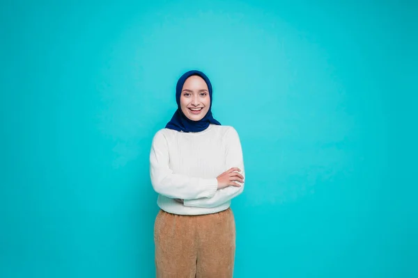 一个自信微笑的亚洲穆斯林女人的画像 她身穿白衬衫 头戴头巾 双手交叉地站在一起 凝视着蓝色背景下被隔离的相机 — 图库照片