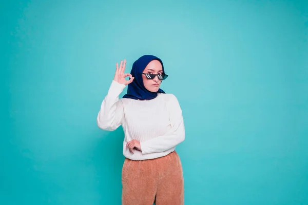 Портрет Улыбающейся Азиатской Мусульманки Очках Подающей Жест Изолированный Синем Фоне — стоковое фото