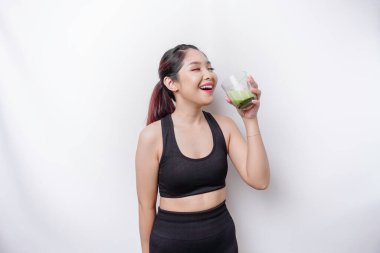 Neşeli Asyalı kadın spor giysisi ve bir bardak lezzetli yeşil smoothie ile beyaz arka planda izole edilmiş..
