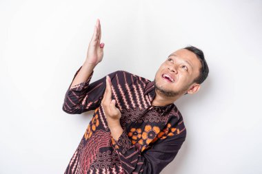 Batik tişört giyen heyecanlı Asyalı adam üzerindeki fotokopi alanını işaret ediyor, beyaz arka planla izole edilmiş.