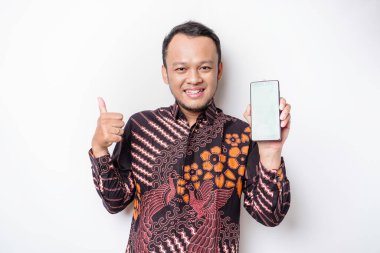 Batik gömlek giyen gülümseyen Asyalı bir adamın portresi ve telefonunda beyaz arka planla izole edilmiş yeşil ekran var.