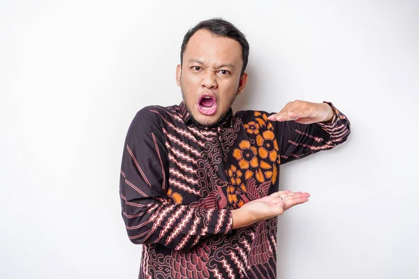 The angry and mad face of Asian man in batik shirt isolated white background.