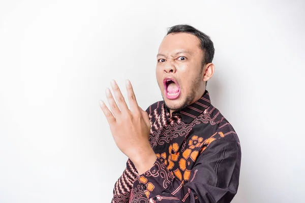 The angry and mad face of Asian man in batik shirt isolated white background.