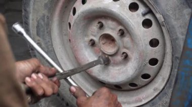 Hands replace tires on wheels with steel tools